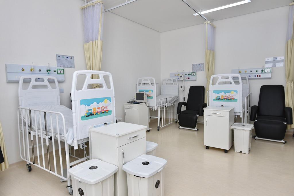 Foto de clínica - A grande sala branca conta com três  camas de UTI  neonatal com desenhos coloridos